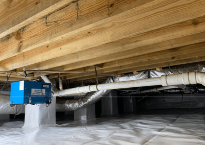 Encapsulated crawlspace with a vapor barrier installed and a blue dehumidifier unit visible, showing a clean, moisture-protected space.