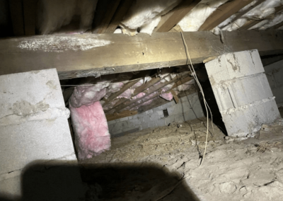 Unfinished crawl space with exposed dirt floor, block foundation, and deteriorating insulation needing repair.