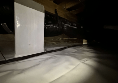 Crawl space with an encapsulated vapor barrier, insulated ducts, and reinforced supports for added stability.